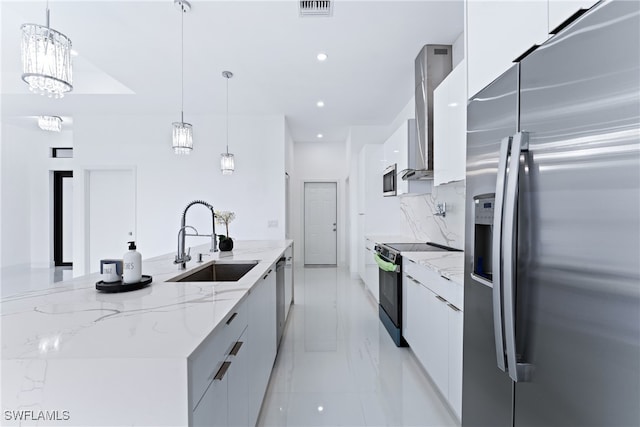 kitchen featuring white cabinets, hanging light fixtures, a large island with sink, sink, and stainless steel appliances