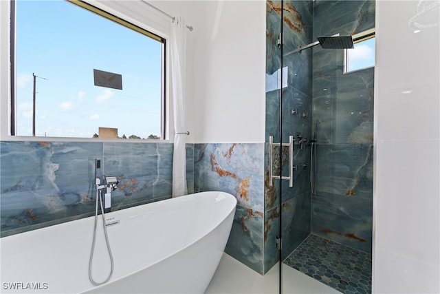 bathroom with a healthy amount of sunlight, plus walk in shower, and tile walls