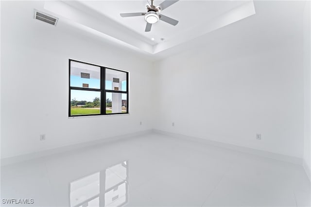 tiled spare room featuring ceiling fan and a raised ceiling