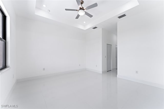 unfurnished room featuring ceiling fan and a raised ceiling