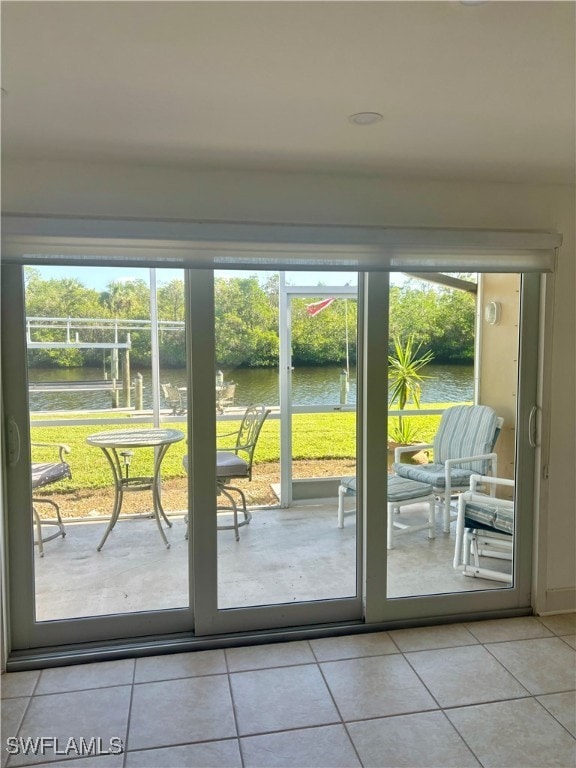 doorway to outside with a wealth of natural light, a water view, and light tile patterned floors