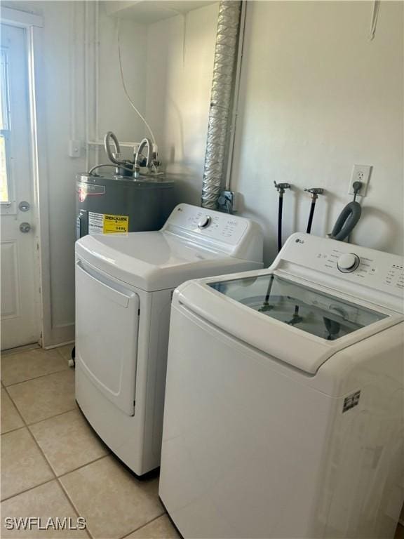 1310 Thompson St, North Fort Myers, FL 33903 - laundry room featuring water heater, light tile patterned floors, and washing machine and clothes dryer