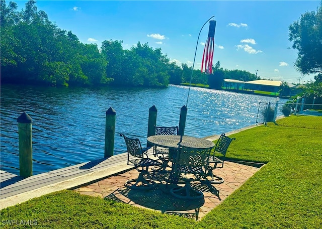 view of dock featuring a water view, a yard, and a patio area