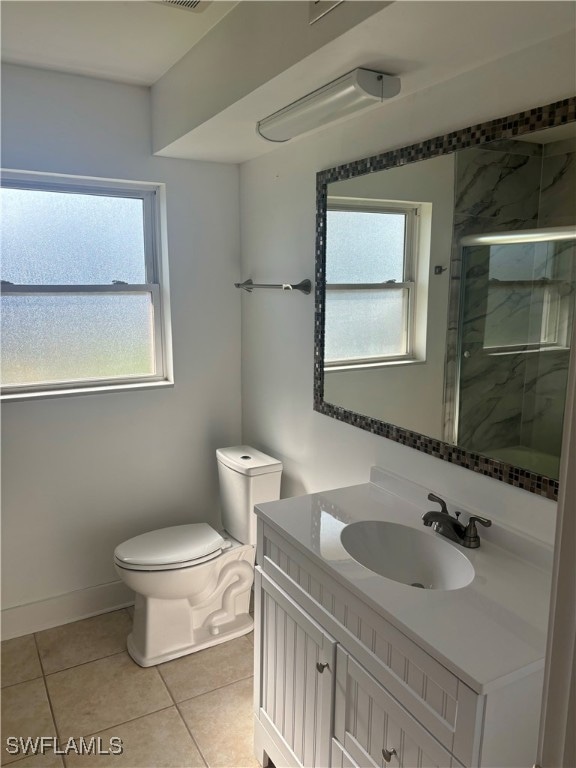 bathroom featuring an enclosed shower, vanity, tile patterned floors, and toilet