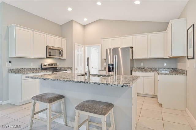 kitchen with light stone countertops, an island with sink, appliances with stainless steel finishes, and white cabinets