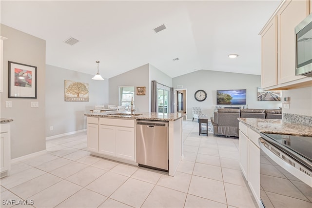 kitchen with light stone counters, decorative light fixtures, vaulted ceiling, a center island with sink, and appliances with stainless steel finishes