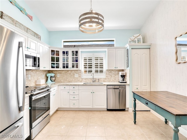 kitchen with hanging light fixtures, white cabinetry, sink, and stainless steel appliances