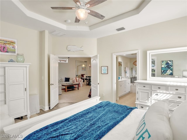 bedroom with connected bathroom, a raised ceiling, and ceiling fan