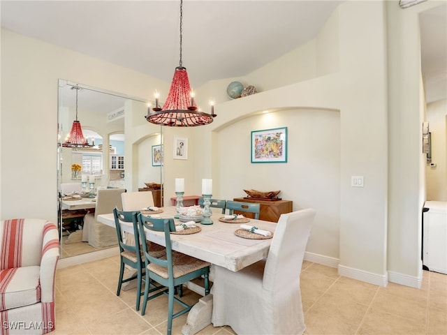 dining area featuring light tile patterned floors, vaulted ceiling, and an inviting chandelier