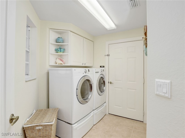 washroom featuring cabinets, washer and clothes dryer, and light tile patterned flooring