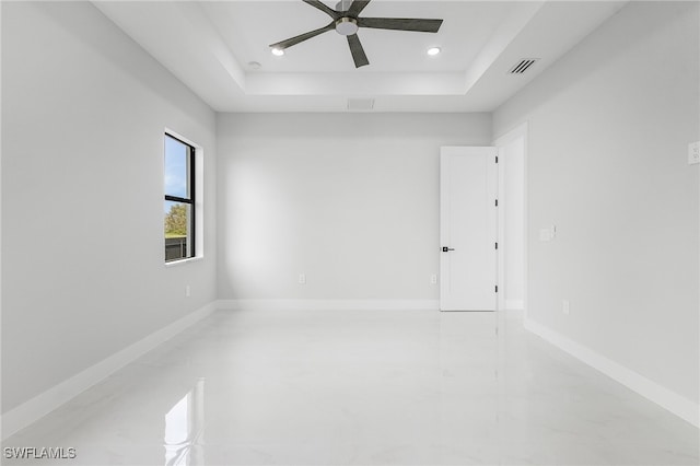 empty room featuring ceiling fan and a raised ceiling