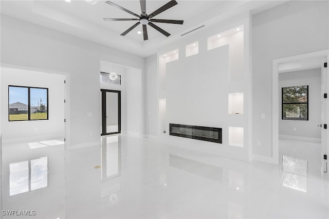 unfurnished living room with a wealth of natural light, ceiling fan, and light tile patterned floors