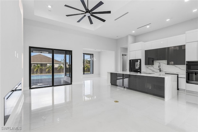 kitchen featuring a kitchen island, white cabinetry, sink, double oven, and ceiling fan