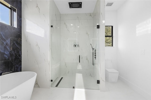 bathroom featuring toilet, a healthy amount of sunlight, and separate shower and tub