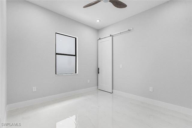 empty room with a barn door and ceiling fan