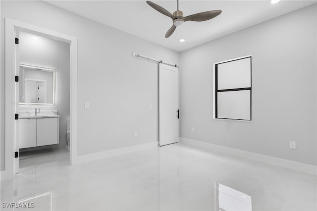 unfurnished bedroom with sink, ensuite bathroom, ceiling fan, light tile patterned floors, and a barn door