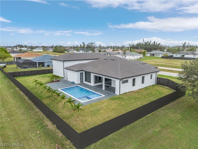 rear view of property with a fenced in pool, a patio, and a lawn