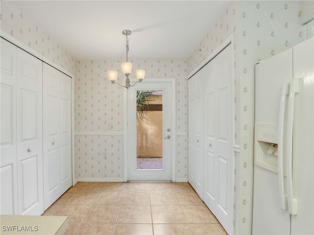 unfurnished dining area with light tile patterned floors and an inviting chandelier