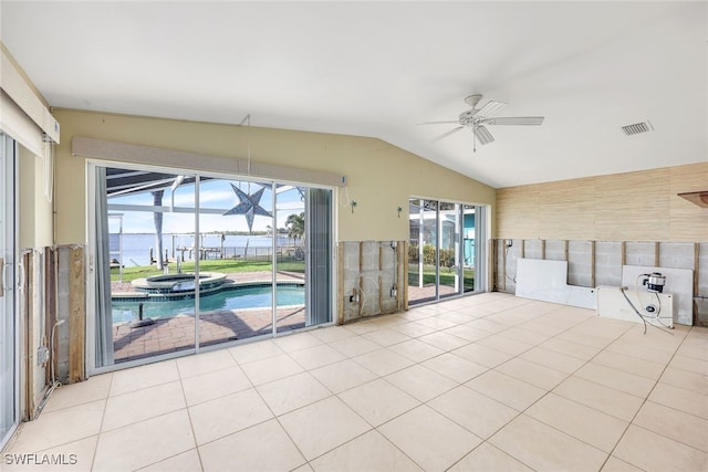 unfurnished living room with a wealth of natural light, a water view, light tile patterned floors, and ceiling fan