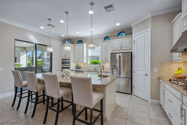 kitchen featuring a center island with sink, stainless steel appliances, a kitchen bar, light stone countertops, and hanging light fixtures