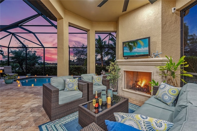 patio terrace at dusk featuring an outdoor living space with a fireplace and glass enclosure