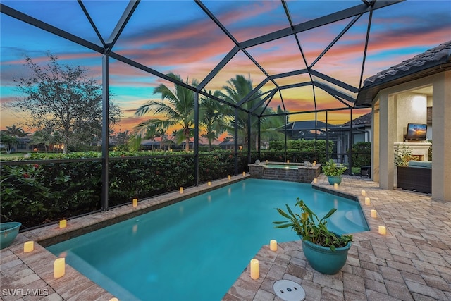 pool at dusk with a patio, a lanai, and an in ground hot tub