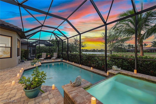 pool at dusk with a lanai, a patio, and an in ground hot tub