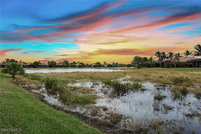 yard at dusk featuring a water view