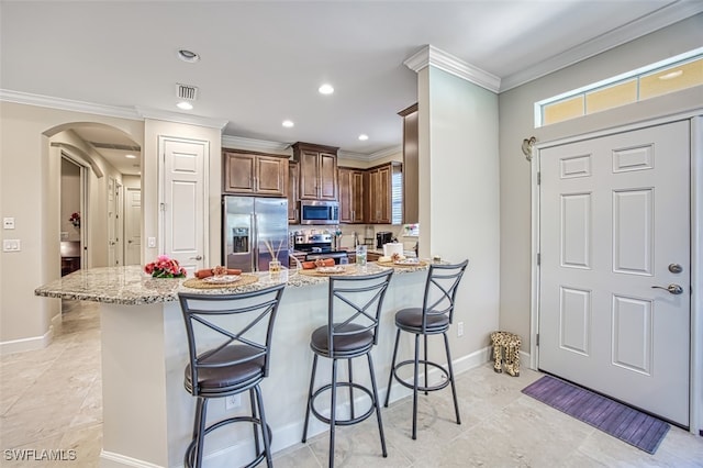 kitchen featuring light stone counters, crown molding, stainless steel appliances, a breakfast bar, and kitchen peninsula