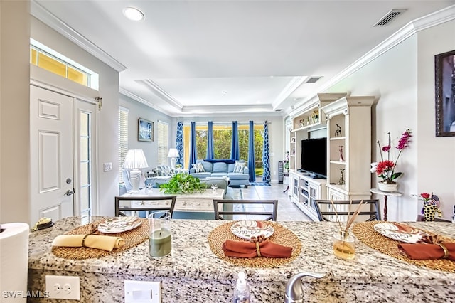 kitchen with light tile patterned flooring, crown molding, a raised ceiling, and light stone counters