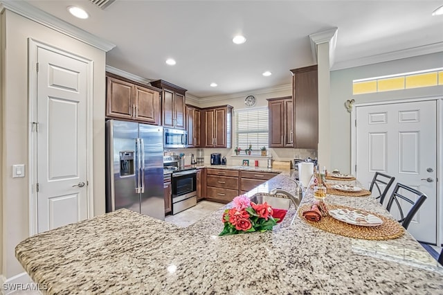 kitchen featuring stainless steel appliances, kitchen peninsula, sink, ornamental molding, and light stone countertops