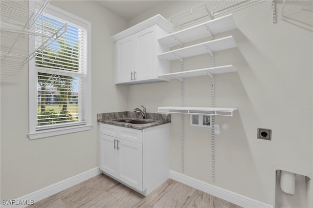 washroom with hookup for an electric dryer, sink, and light hardwood / wood-style floors