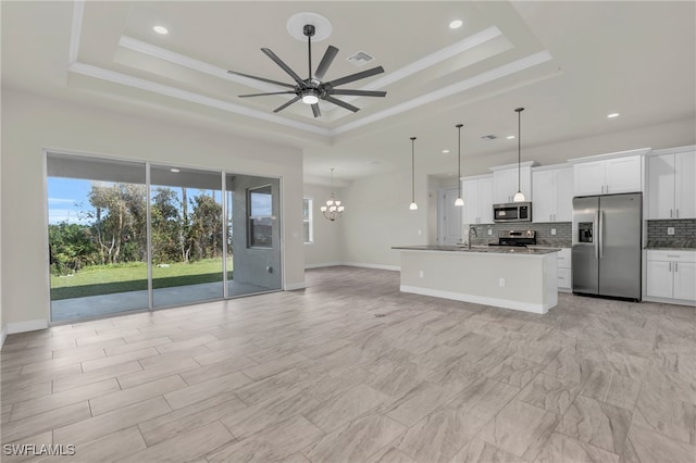 kitchen featuring a raised ceiling, appliances with stainless steel finishes, pendant lighting, and white cabinets