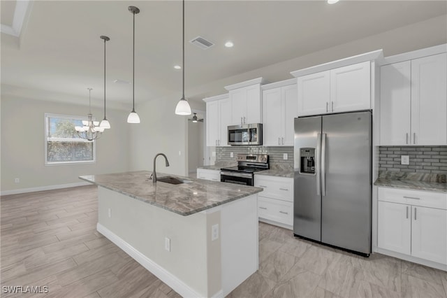 kitchen with appliances with stainless steel finishes, sink, pendant lighting, and white cabinets