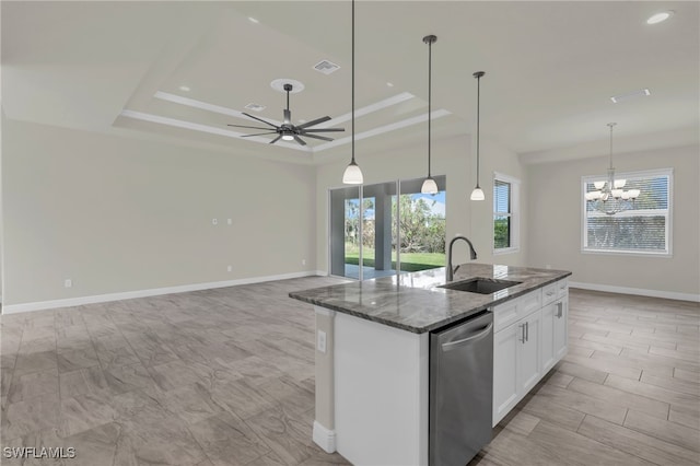 kitchen featuring sink, dark stone counters, stainless steel dishwasher, white cabinets, and a center island with sink