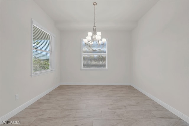 unfurnished room with a notable chandelier