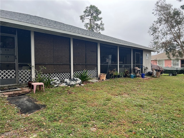 back of property with a lawn and a sunroom