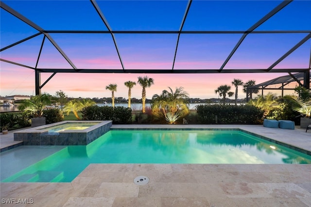 pool at dusk with a lanai, a patio area, an in ground hot tub, and a water view