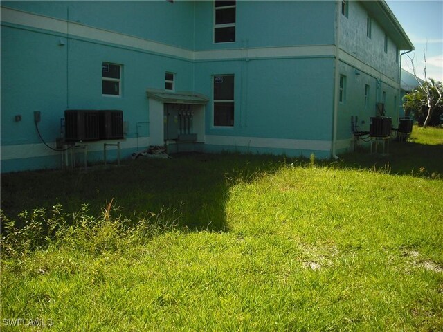 back of house with central air condition unit and a yard