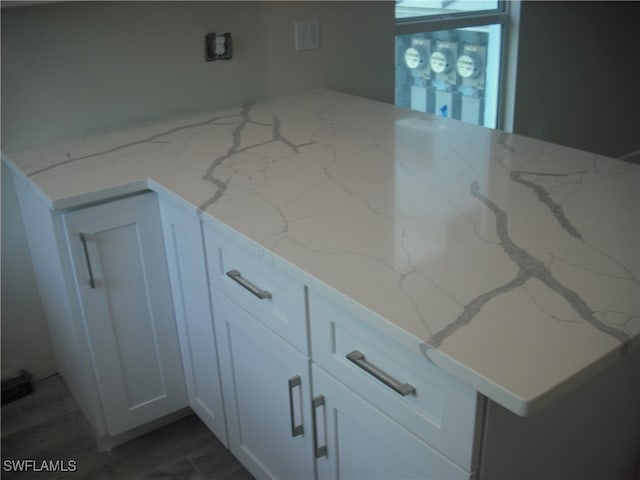 room details featuring dark hardwood / wood-style flooring, white cabinetry, and light stone counters