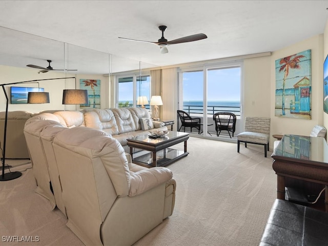 living room with ceiling fan, light colored carpet, and a water view