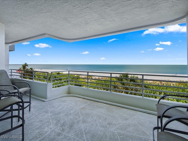 balcony featuring a view of the beach and a water view