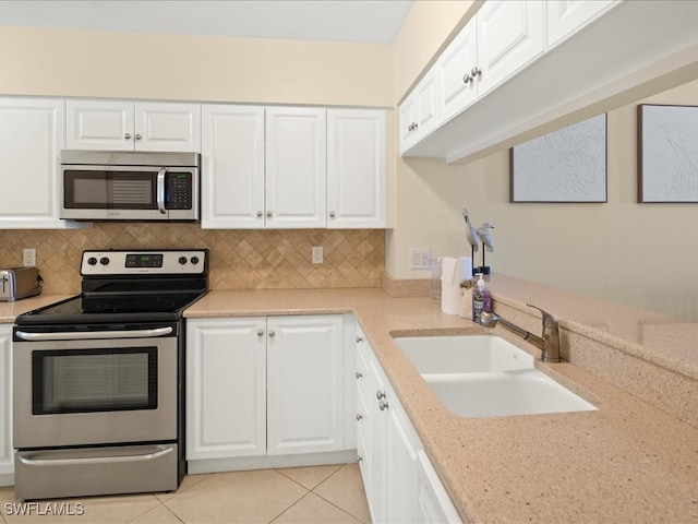 kitchen featuring stainless steel appliances, white cabinetry, sink, tasteful backsplash, and light tile patterned floors