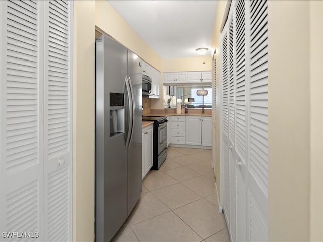 kitchen with white cabinets, appliances with stainless steel finishes, light tile patterned flooring, and sink