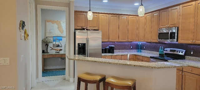 kitchen featuring crown molding, stainless steel appliances, light stone countertops, decorative backsplash, and a breakfast bar area