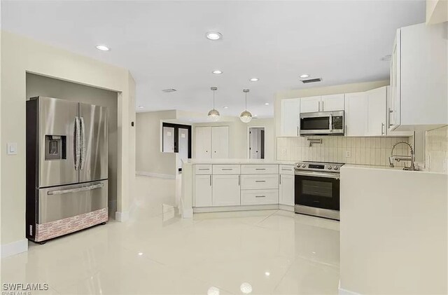 kitchen with white cabinetry, appliances with stainless steel finishes, hanging light fixtures, and tasteful backsplash