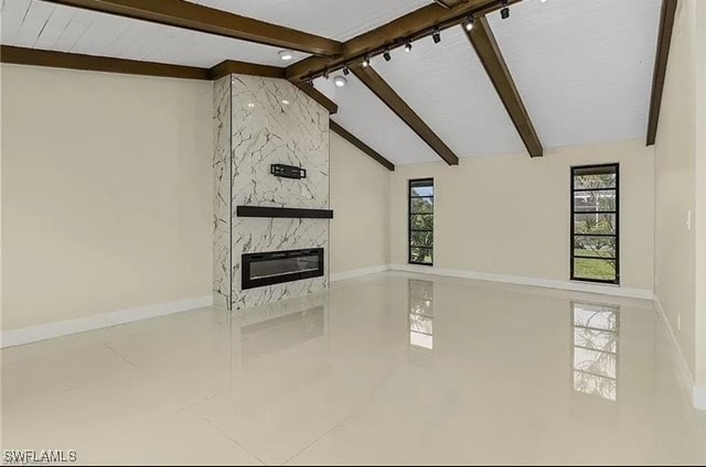 unfurnished living room featuring a high end fireplace, plenty of natural light, and lofted ceiling with beams