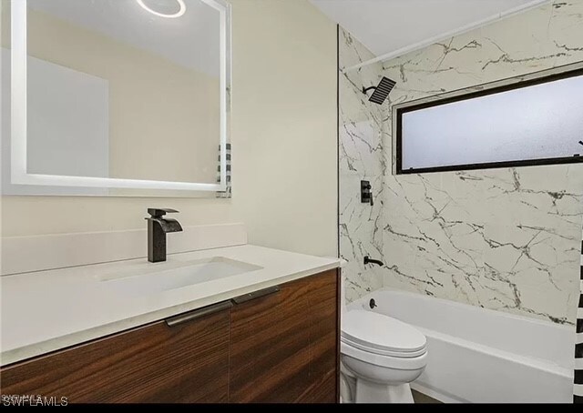 full bathroom with toilet, vanity, and tiled shower / bath