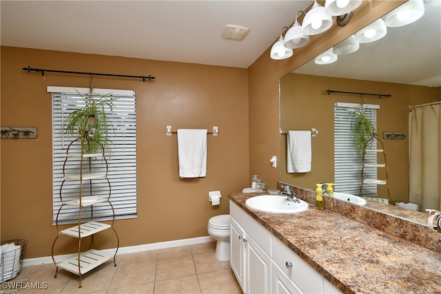 bathroom featuring vanity, toilet, a healthy amount of sunlight, and tile patterned flooring