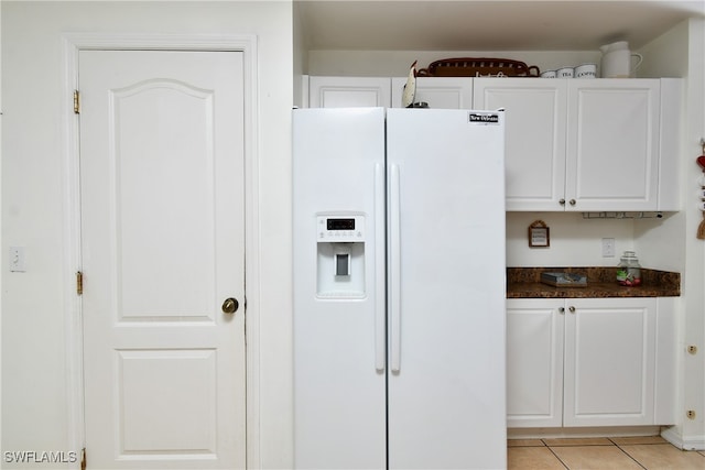 kitchen featuring white fridge with ice dispenser, white cabinets, and light tile patterned flooring